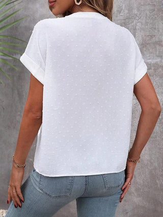 Haut blanc à manches courtes bouffantes, dos visible avec pois discrets et absence de boutons