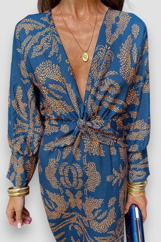 Robe midi bleue à encolure V, nœud torsadé au buste, motif floral doré, manches longues.