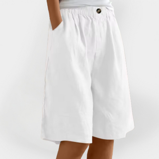 Short en lin blanc, taille élastique, poches latérales, bouton métal sur la ceinture.