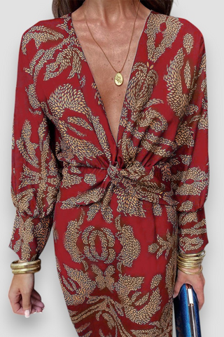 Robe midi rouge à encolure V, nœud noué torsadé et motif floral doré.