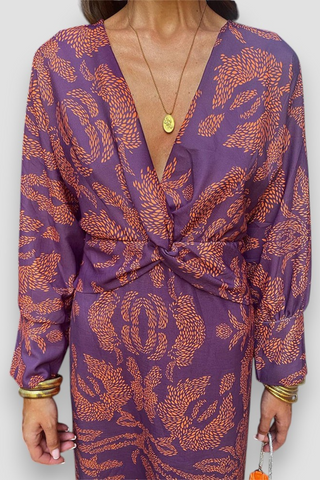 Robe midi violette, encolure V, nœud torsadé devant et motif floral orange-doré.