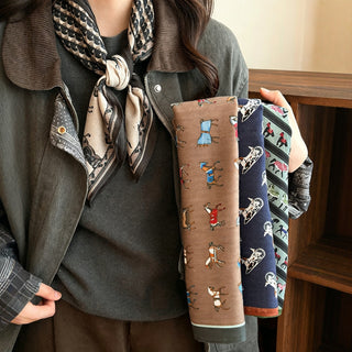 Foulard en soie imprimé chevaux, fond beige clair et bordure sombre, noué.
