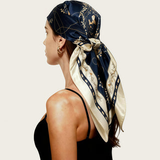 Foulard carré en satin bleu marine à motifs, noué sur la tête, tissu lustré.