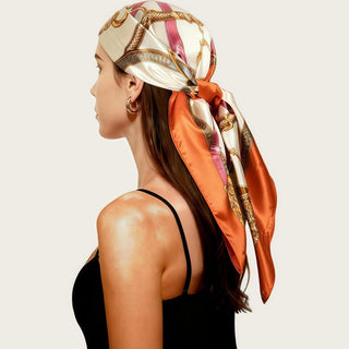 Foulard carré en satin orange et motifs cachemire, noué sur la tête, tissu lustré.