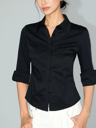 Chemise noire ajustée à boutons dissimulés et manches retroussées.