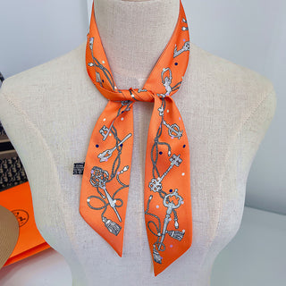 Foulard étroit orange à motifs de clés et chaînes, noué au cou