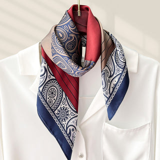 Foulard carré en soie bleu marine, blanc et rouge, motifs cachemire, noué au cou.