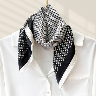 Foulard carré en soie noir et blanc, motif pied-de-poule, noué au cou.