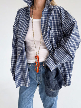 Chemise à carreaux bleus et blancs, ouverte sur un débardeur, avec poche poitrine.