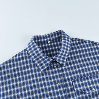 Détail de la chemise à carreaux bleus et blancs, col, boutons et poche poitrine.
