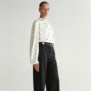 Blouse blanche à pois noirs, col drapé haut et manches bouffantes amples