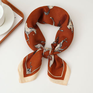 Foulard en soie imprimé chevaux, orange brique avec liseré beige, plié.