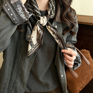 Foulard en soie imprimé chevaux, fond beige et marron, bordure noire, noué.