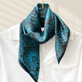 Foulard carré en soie bleu turquoise à motifs cachemire, noué au cou.