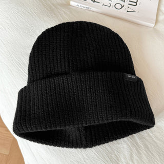 Bonnet en laine noir, maille côtelée, revers large, étiquette noire sur le bord