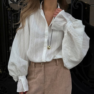 Chemise blanche à col classique, boutonnée devant, manches longues amplettes bouffantes.