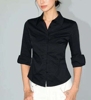 Chemise noire cintrée à col classique, manches retroussées et fermeture boutonnée.
