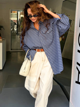 Chemise ample à carreaux bleus et blancs, portée avec les manches longues retroussées.