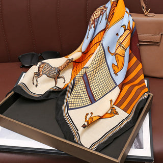 Foulard en soie imprimé chevaux, fond orange, rayures et bord noir, plié.