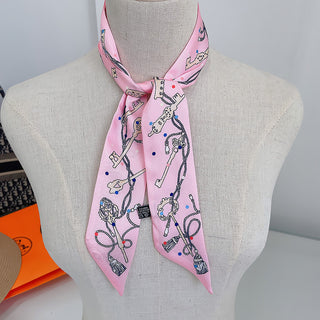Foulard étroit rose à motifs de clés et chaînes, noué au cou