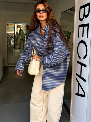 Chemise à carreaux bleus et blancs, coupe longue et ample, portée rentrée à la taille.