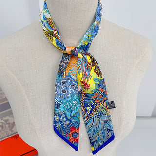 Foulard étroit à imprimé floral multicolore sur fond bleu, noué au cou