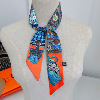 Foulard étroit orange à glands bleus, porté noué autour du cou
