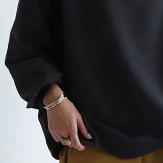 Pull noir oversize, gros plan sur la manche ample et le poignet froncé