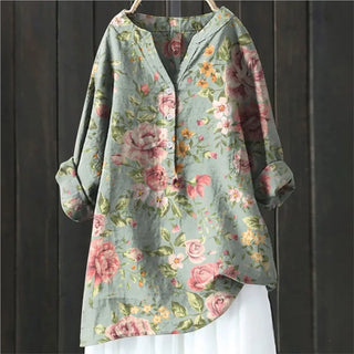 Blouse bleu clair à fleurs roses et motifs feuillus, col boutonné.