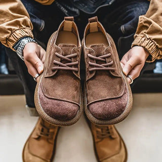 Paire de chaussures en cuir de veau marron, lacets et semelle robuste.