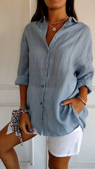 Chemise ample en coton bleue boutonnée, col chemise, manches retroussées.