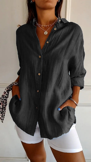 Chemise ample en coton noire boutonnée, col chemise, manches retroussées.
