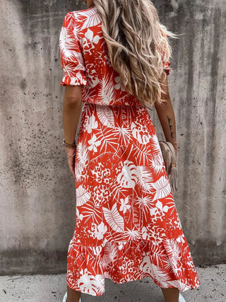 Robe rouge à motif floral blanc, manches bouffantes, col V boutonné, fente latérale.