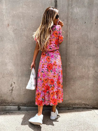 Robe fleurie rose à manches bouffantes, col V et patte de boutonnage, fente côté.